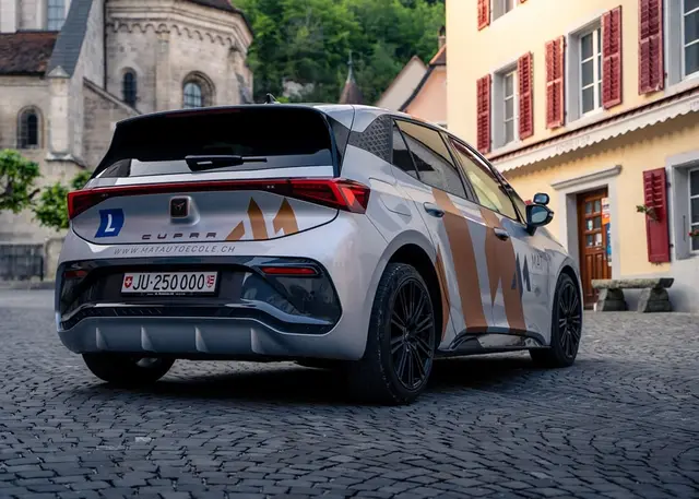La Cupra aux couleurs de Mat Auto École dans une rue pavée du Jura